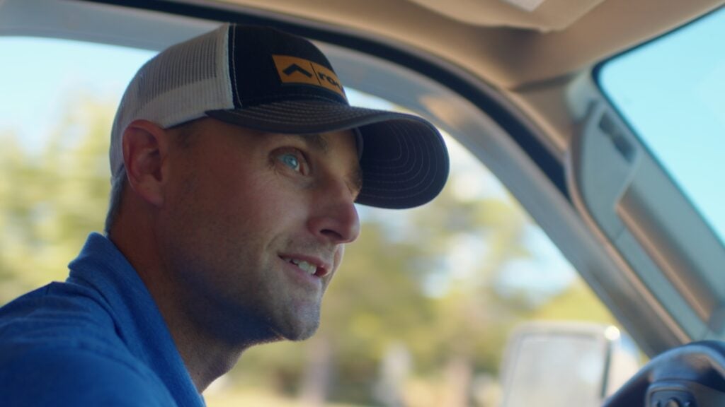 man in a quality roofing solutions ballcap sitting in a car