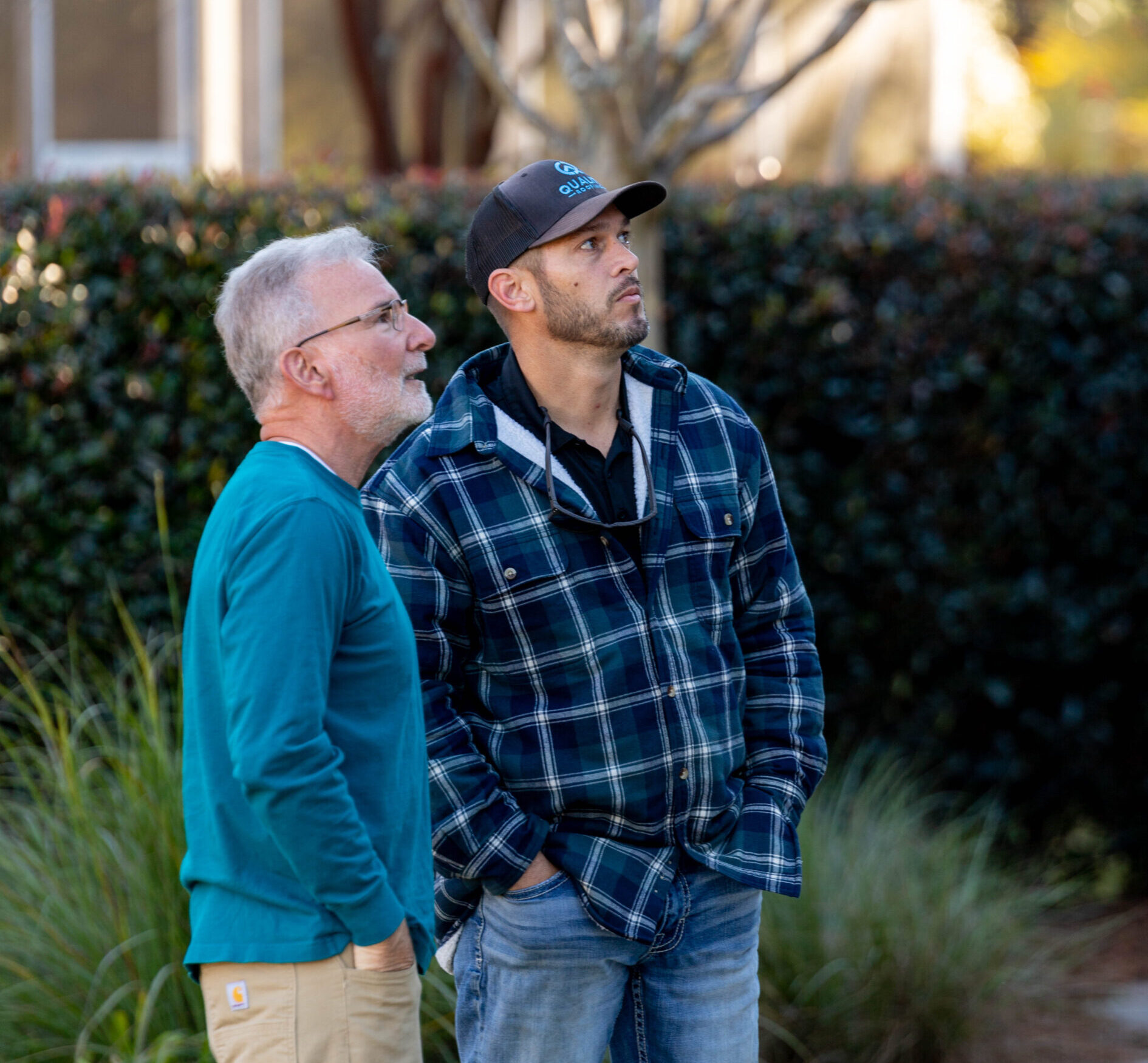 two men looking at a roof from the ground