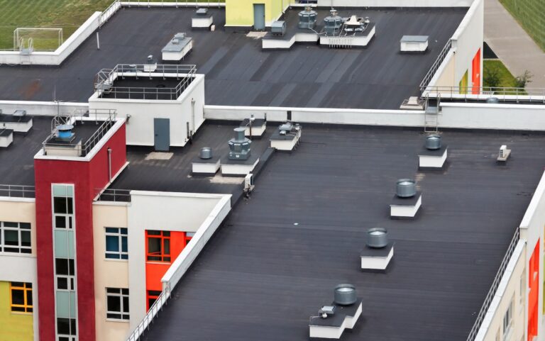 Top view dark flat roof with air conditioners of a modern white red yellow apartment building.