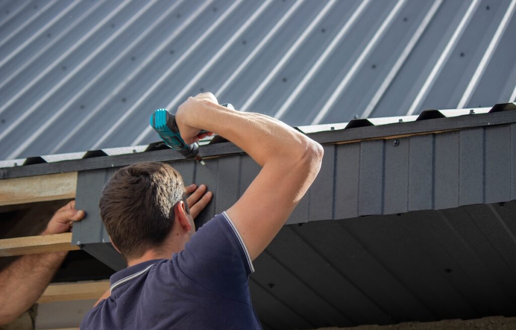 Man Installing Roof Panels with a Drill.