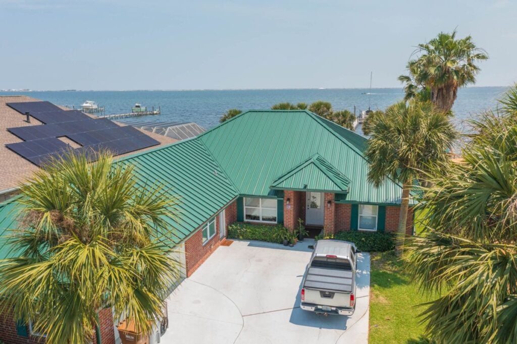 house with green metal roof next to the ocean
