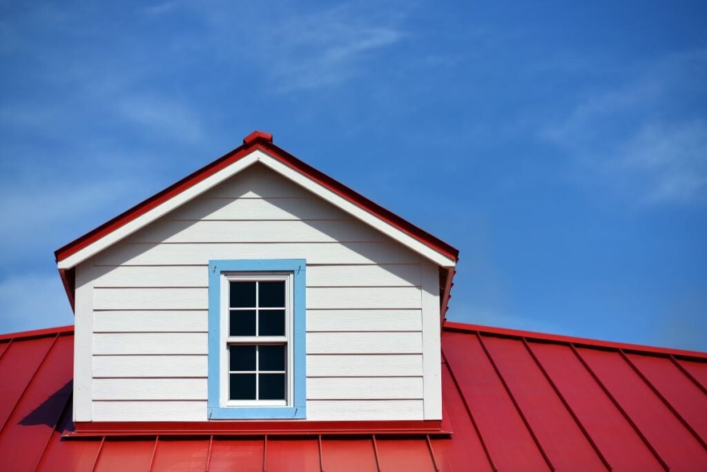 Metal roof vs tile roof close up red and white house blue sky