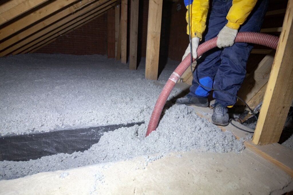 best attic insulation worker using hose to spread cellulose