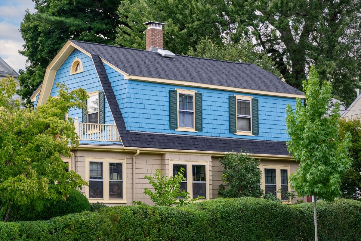 gambrel roof beautiful blue house surrounded by trees summer time