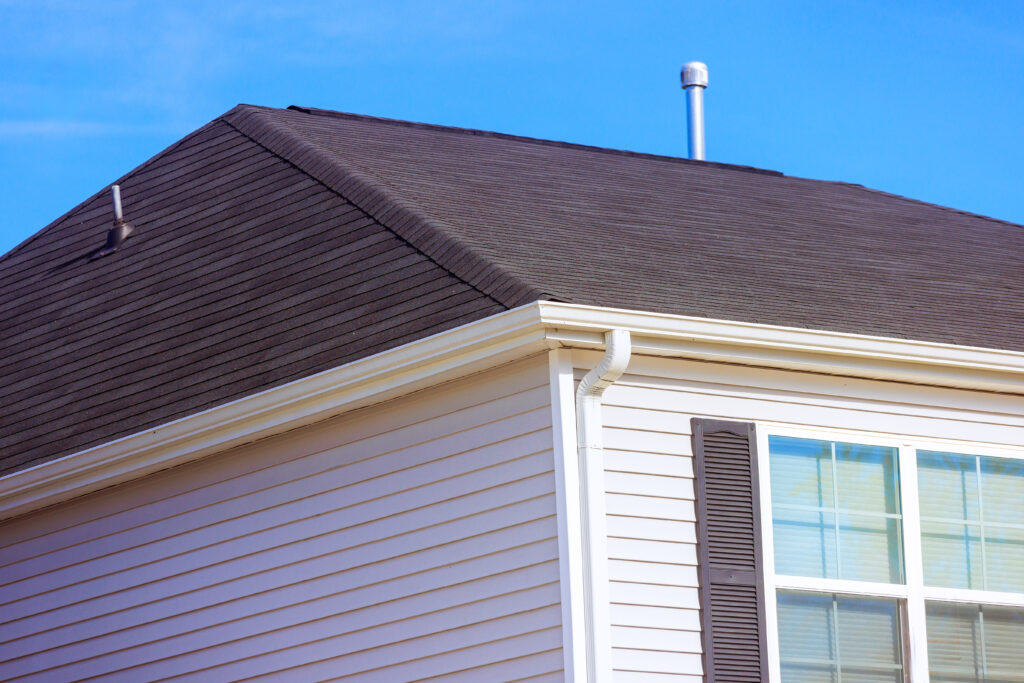 Well maintained residential roof white siding home displays neat gutters,