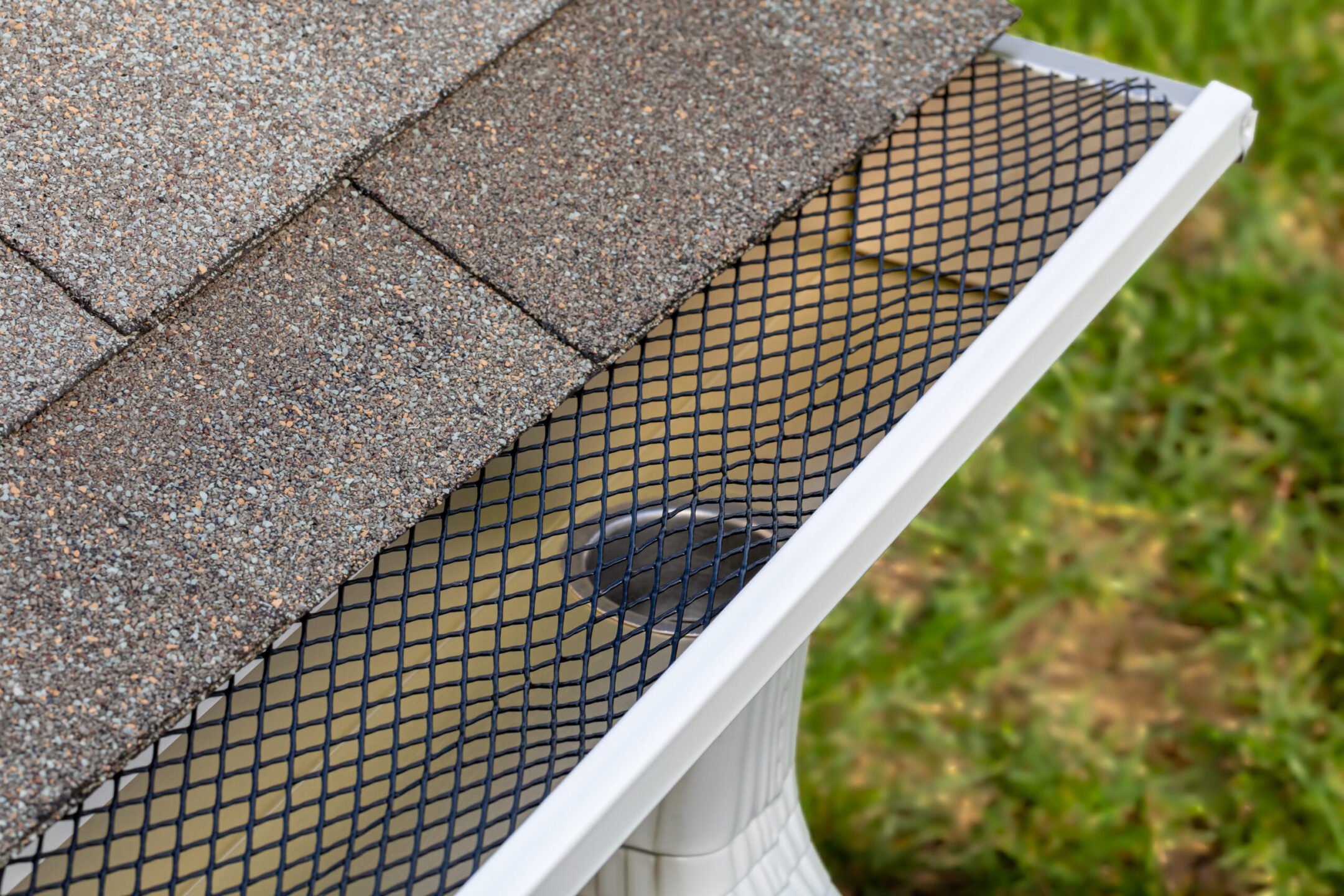 Installing gutter guard mesh screen on rain guttering.