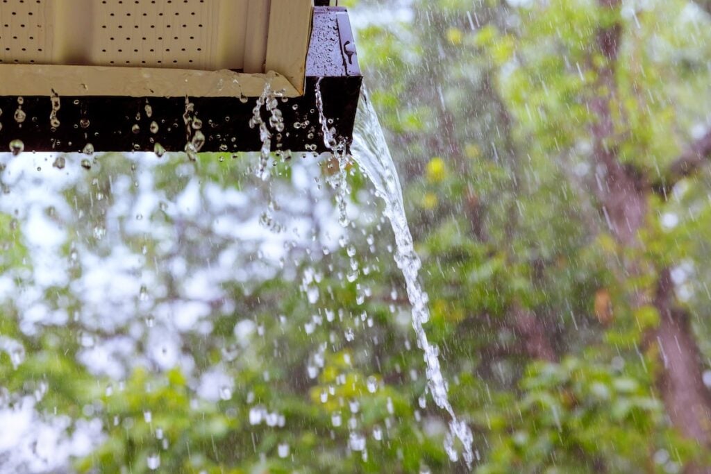 During heavy rain, water cascades from overflowing gutters.