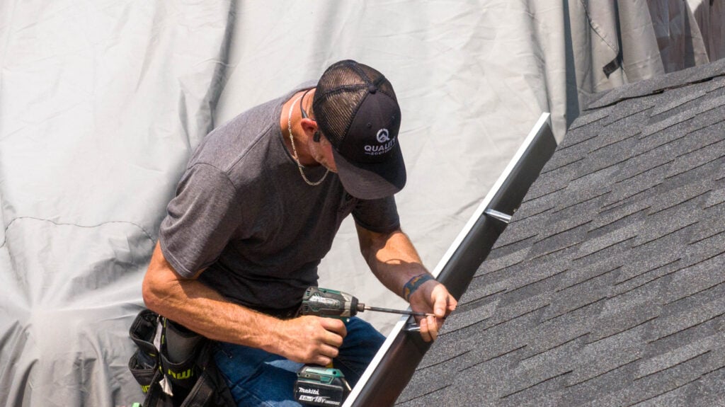 Man installing gutter on roof