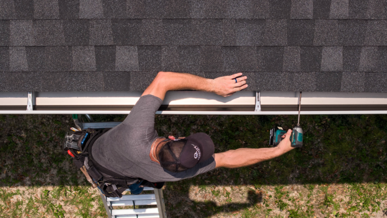 Man installing gutter from ladder