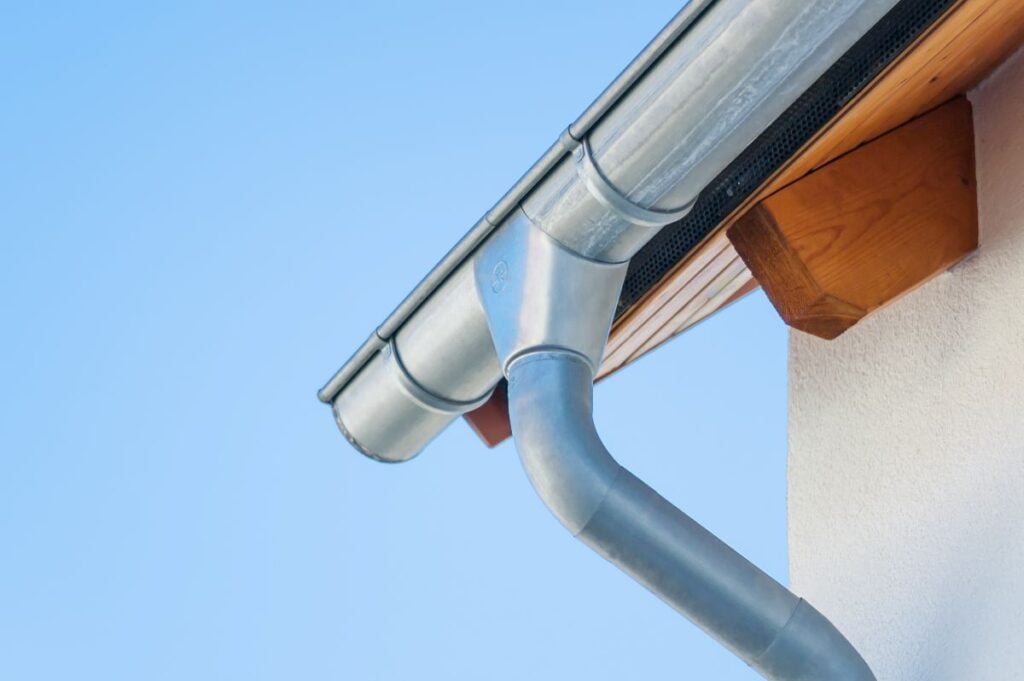Corner of a house with gutters on a background of blue sky