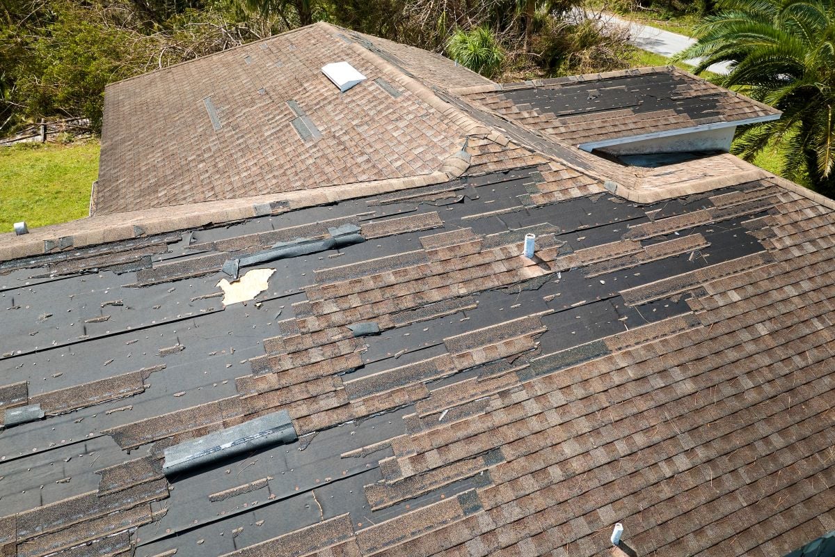 Damaged house roof with missing shingles after hurricane Ian in Florida