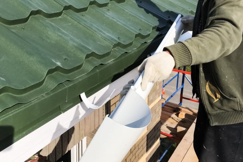 Workers work to assemble the roof and drainage system.