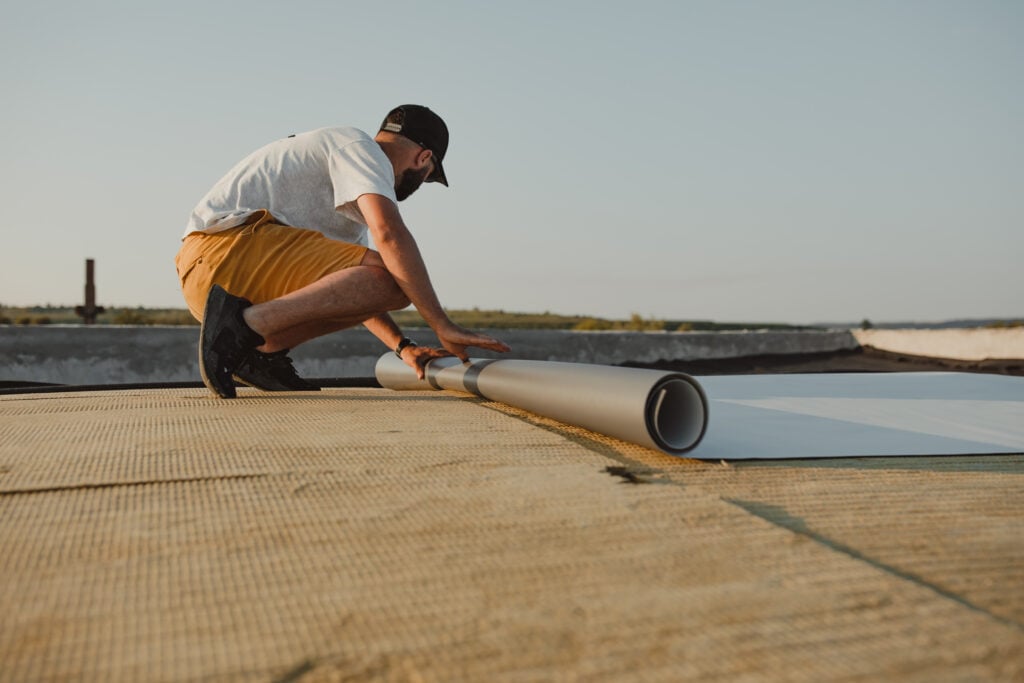 roof waterproofing services guy unrolling membrane