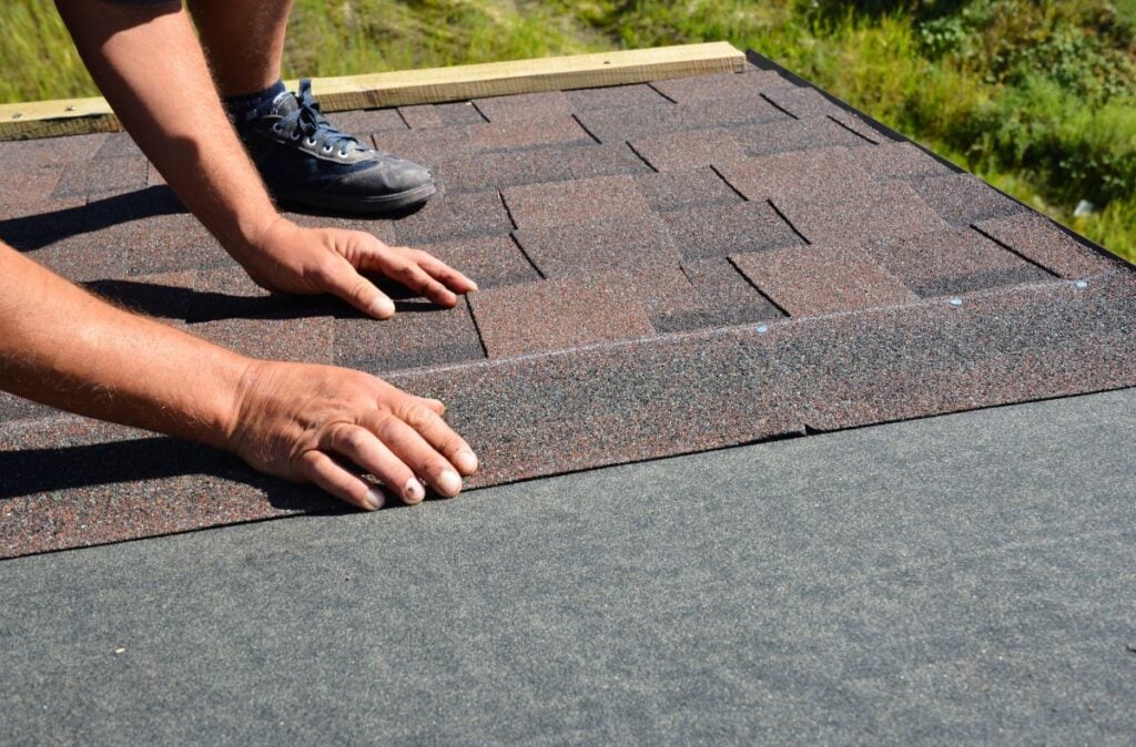 guy installing brown shingles roof