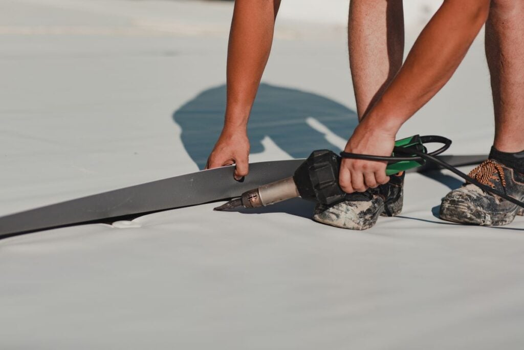 guy using heating gun on tpo white roof